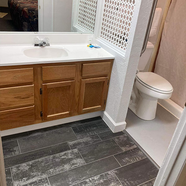 A clean bathroom area with a counter and sink area and a toilet and shower area.