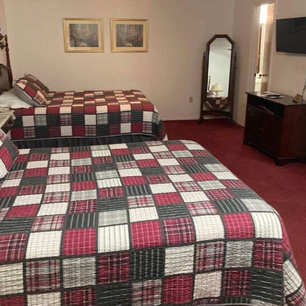 A clean hotel room with two queen beds, a dresser, tv and full length mirror